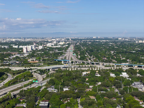 Aerial view of the Interstate 95 highway interchange surrounded by lush green trees and urban development in Miami, Florida, United States.