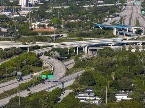 Aerial view of Interstate 95 Express highway interchange with multi-level concrete overpasses, lush green trees, and urban infrastructure in Miami, Florida, United States.