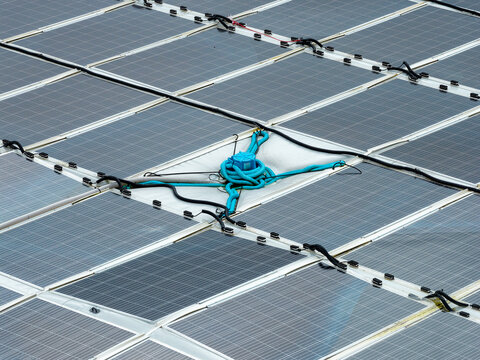Aerial view of a circular floating solar power plant on the water surface with interconnected panels and blue cabling in Liabygda, More og Romsdal, Norway.