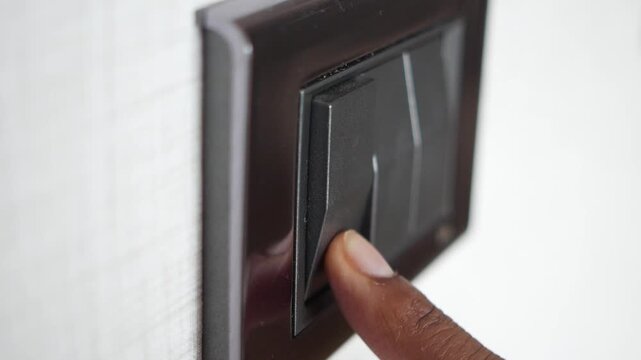 Close up of finger pressing black light switch on wall in slow motion