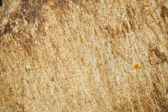 Weathered golden brown rock face with natural diagonal mineral streaks
