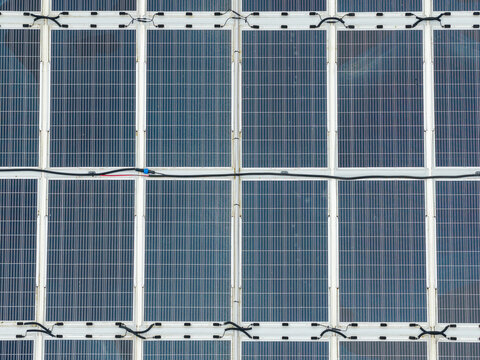 Aerial view of a circular floating solar power plant on the water surface with interconnected panels and electrical wiring in Liabygda, More og Romsdal, Norway.