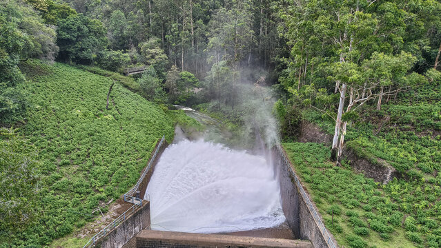 Controlled water release at Kundala Dam spillway amidst green hills in Munnar, Kerala, India