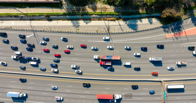 Aerial view of heavy traffic on a multi-lane highway with various cars and trucks moving in both directions in Los Angeles, California, United States.