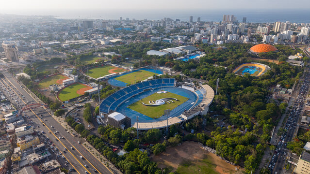 Aerial view of the Centro Olimpico Juan Pablo Duarte with its stadium, athletic track, and baseball fields set amidst urban parkland in Santo Domingo, Distrito Nacional, Dominican Republic.