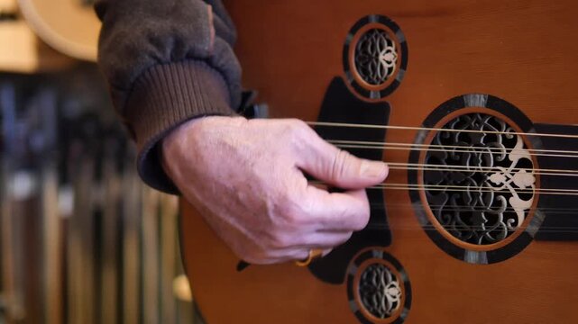 A musician's hand expertly plucking strings of traditional oud instrument creating beautiful melody in a warm rustic setting