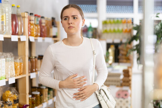 Young woman with stomach pain in grocery store