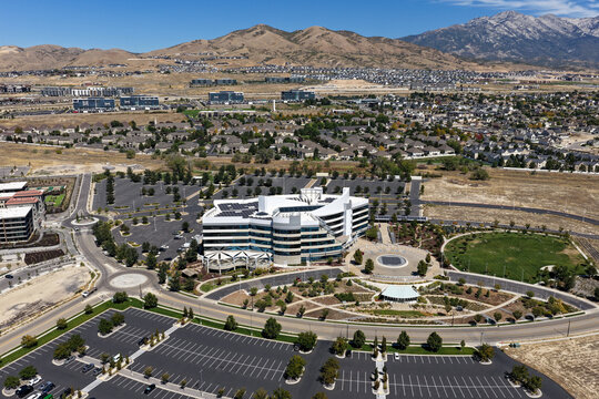 Aerial view of Silicon Slopes business park featuring modern office buildings with solar panels, traffic circles, landscaped grounds, and parking lots in Lehi, Utah, United States.