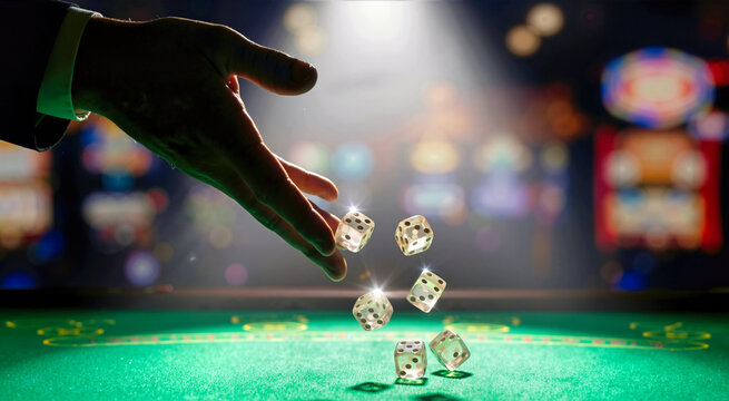 Silhouetted hand tossing clear transparent dice onto green felt gambling table under bright spotlight glare. Casino craps game night scene with dramatic lighting and background bokeh lights
