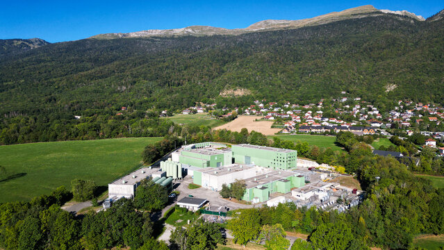 Aerial view of the European Center for Nuclear Research CERN facility nestled in a green valley with surrounding forests and mountains near Echenevex, Auvergne-Rhone-Alpes, France.