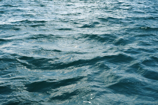 background with blue sea waves on the water surface. The texture of the ocean waves