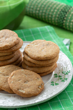 Cookies are stacked on a shamrock plate with green napkins and bowls in the background