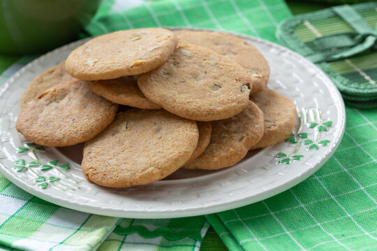 Cookies on a white shamrock plate with green decorations placed on a green checkered tablecloth
