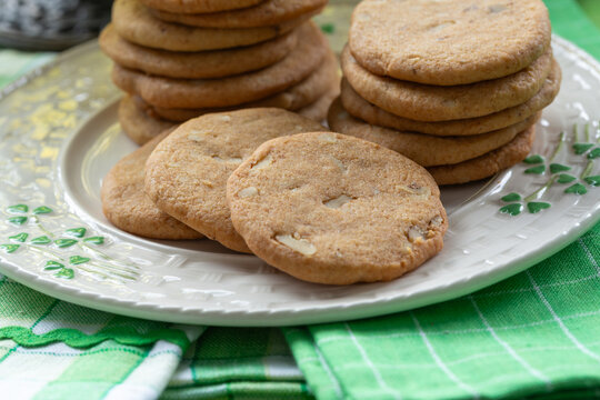 Freshly baked cookies on a decorative shamrock plate with green accents placed on a checkered tablecloth