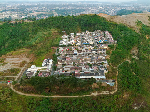 Aerial view of a residential neighborhood with rows of houses nestled on a green hillside overlooking the urban landscape in Kota Samarinda, Kalimantan Timur, Indonesia.