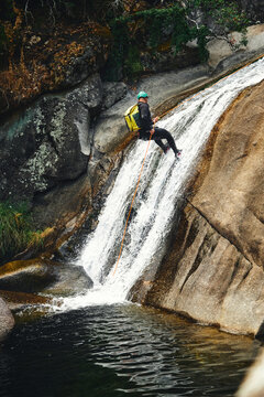Action shot of a canyoner rappelling down a cascading rocky waterfall