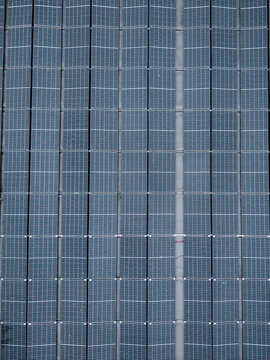 Aerial view of rows of blue solar panels arranged in a grid pattern on a rooftop in Riga, Latvia.