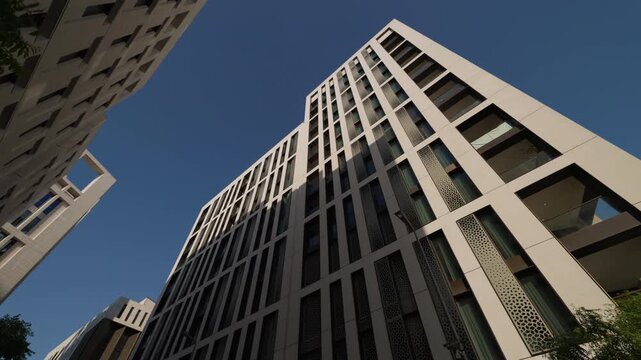 Upward view of a tall contemporary office building defined by pale stone framing and a strict vertical window pattern.