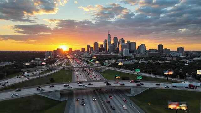 Aerial city skyline sunset over busy highway interchange with commuter traffic cityscape
