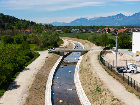 A river restoration project including channel widening and flood embankment work. Aerial view from above captures the surrounding landscape.