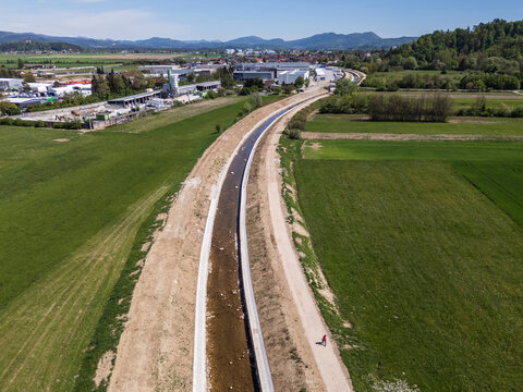 Aerial view of a river restoration project showing channel widening and flood embankment construction in a rural area.