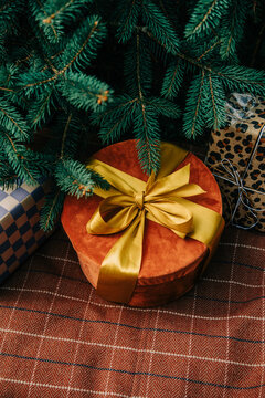 Christmas gift box with bow beside fir branch on brown checkered tablecloth, side view
