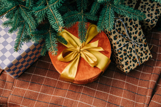 Christmas gift box with bow beside fir branch on brown checkered tablecloth, side view