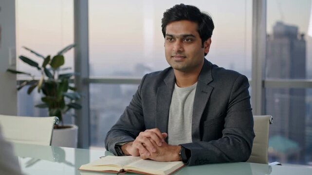Interviewer asking, listening man in grey blazer keeping eye contact at glass table