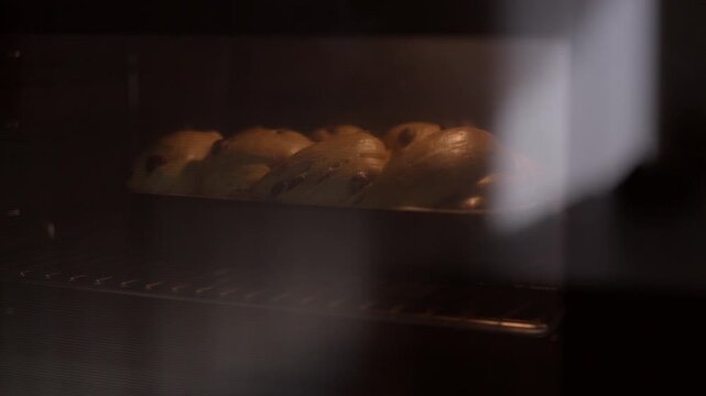 Golden brown bread rolls baking inside a hot oven, seen through the steamy glass door. Freshly baked food concept