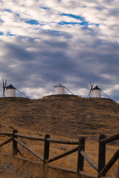 TitleThree Historic Windmills on Hilltop in Consuegra Spain Under Dramatic Cloudy Sky