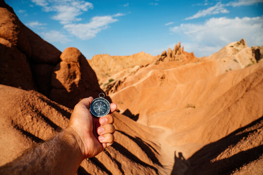 A compass in hand against the backdrop of a canyon &mdash; a fairy‑tale canyon, the Red Canyon in Kyrgyzstan in summer