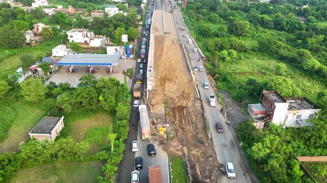 Highway widening project featuring raw earthmoving construction and a congested single-lane detour navigating around an unfinished elevated overpass.