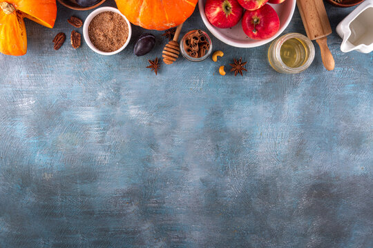Fall baking, cooking seasonal dessert background with various ingredients - honey, pumpkin squash, brown sugar, cinnamon, spices, red apples, plums, walnuts, pecans. Autumn, thanksgiving bakery backgr