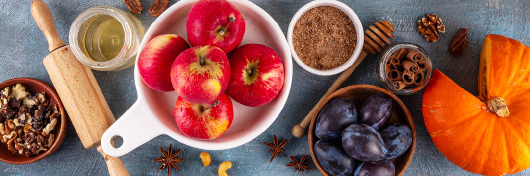 Fall baking, cooking seasonal dessert background with various ingredients - honey, pumpkin squash, brown sugar, cinnamon, spices, red apples, plums, walnuts, pecans. Autumn, thanksgiving bakery backgr