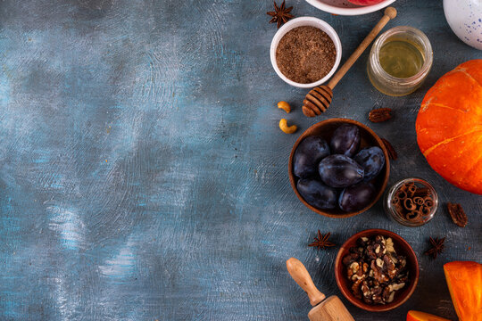 Fall baking, cooking seasonal dessert background with various ingredients - honey, pumpkin squash, brown sugar, cinnamon, spices, red apples, plums, walnuts, pecans. Autumn, thanksgiving bakery backgr