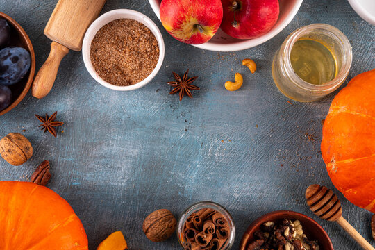 Fall baking, cooking seasonal dessert background with various ingredients - honey, pumpkin squash, brown sugar, cinnamon, spices, red apples, plums, walnuts, pecans. Autumn, thanksgiving bakery backgr