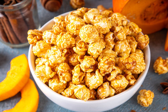 Pumpkin popcorn with caramel and pumpkin spice. Bowl with tasty sweet popcorn covered with pumpkin spice caramel, cinnamon and spices, copy space
