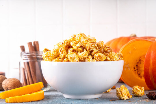Pumpkin popcorn with caramel and pumpkin spice. Bowl with tasty sweet popcorn covered with pumpkin spice caramel, cinnamon and spices, copy space