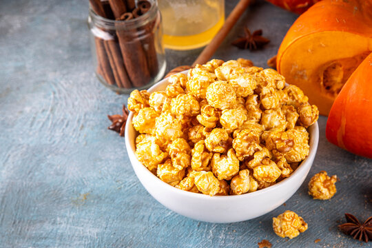 Pumpkin popcorn with caramel and pumpkin spice. Bowl with tasty sweet popcorn covered with pumpkin spice caramel, cinnamon and spices, copy space