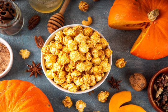Pumpkin popcorn with caramel and pumpkin spice. Bowl with tasty sweet popcorn covered with pumpkin spice caramel, cinnamon and spices, copy space
