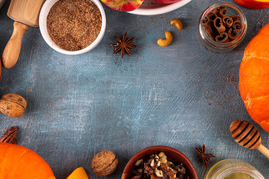 Fall baking, cooking seasonal dessert background with various ingredients - honey, pumpkin squash, brown sugar, cinnamon, spices, red apples, plums, walnuts, pecans. Autumn, thanksgiving bakery backgr