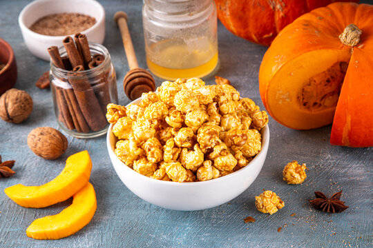 Pumpkin popcorn with caramel and pumpkin spice. Bowl with tasty sweet popcorn covered with pumpkin spice caramel, cinnamon and spices, copy space