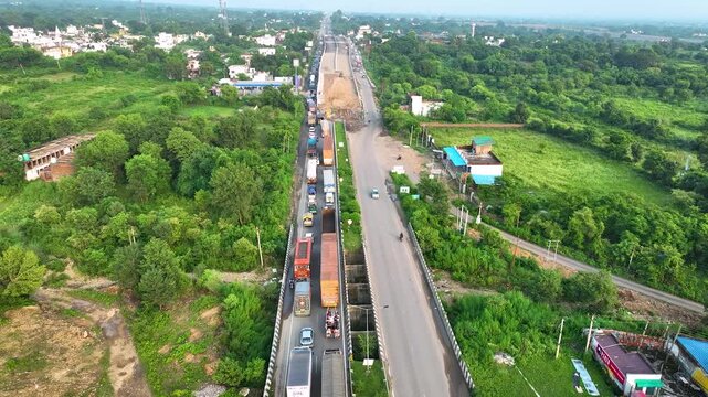 Aerial perspective of a critical infrastructure upgrade showing a soil embankment flyover ramp and heavy traffic gridlock in a rural transit corridor.