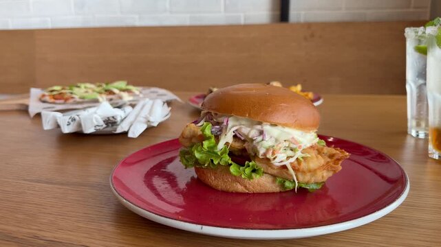 Close-up shot of a crispy chicken burger stacked with fresh lettuce, creamy sauce and a soft toasted bun, showcasing juicy, golden-fried chicken.
