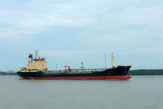 Calm industrial marine vessel sailing across water for international fuel logistics freight transport delivery with serene atmosphere