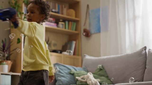 African American boy spinning and shooting soap bubbles with toy blaster in slow motion. Footage suitable for toy commercials, parenting blogs, family campaigns