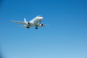 Obraz premium White Commercial Passenger Airplane in Clear Blue Sky on Landing Approach