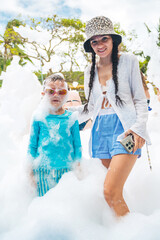 A happy mother with son at a foam party during a summer vacation. A family at resort on a trip © alexkoral
