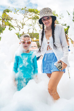 A happy mother with son at a foam party during a summer vacation. A family at resort on a trip