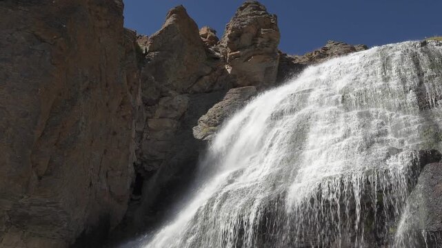 Scenic view of a waterfall cascading down rocky cliffs in 4K slow motion